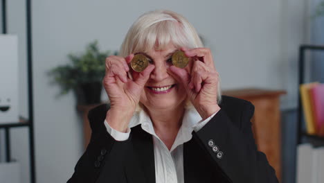 Elderly-businesswoman-showing-golden-bitcoins-BTC,-money-mining,-investment,-wealth,-earning,-income