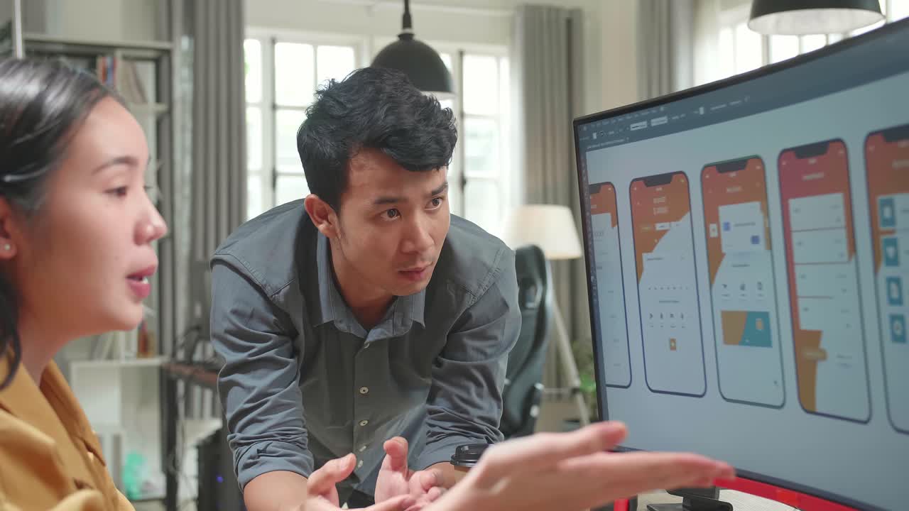 Asian Male And Female Mobile Application Designers Arguing And Discuss New App Features. They Work On A Personal Computer