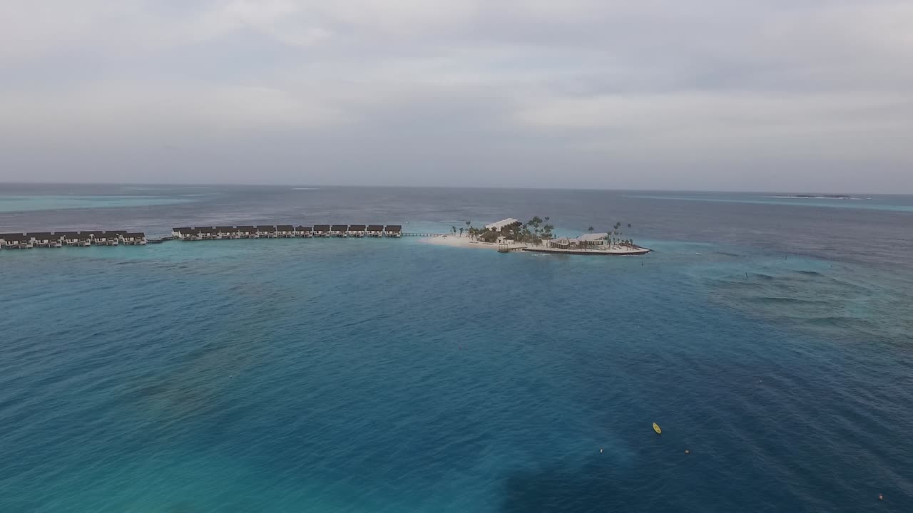 Ripresa con drone di un'isola delle Maldive in mezzo all'oceano, con ville sull'acqua.