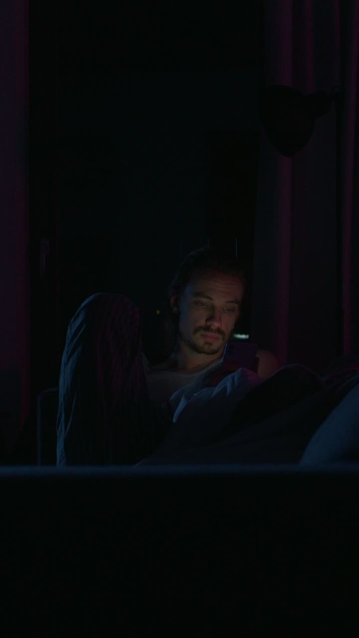 Uomo che usa un telefono a letto di notte