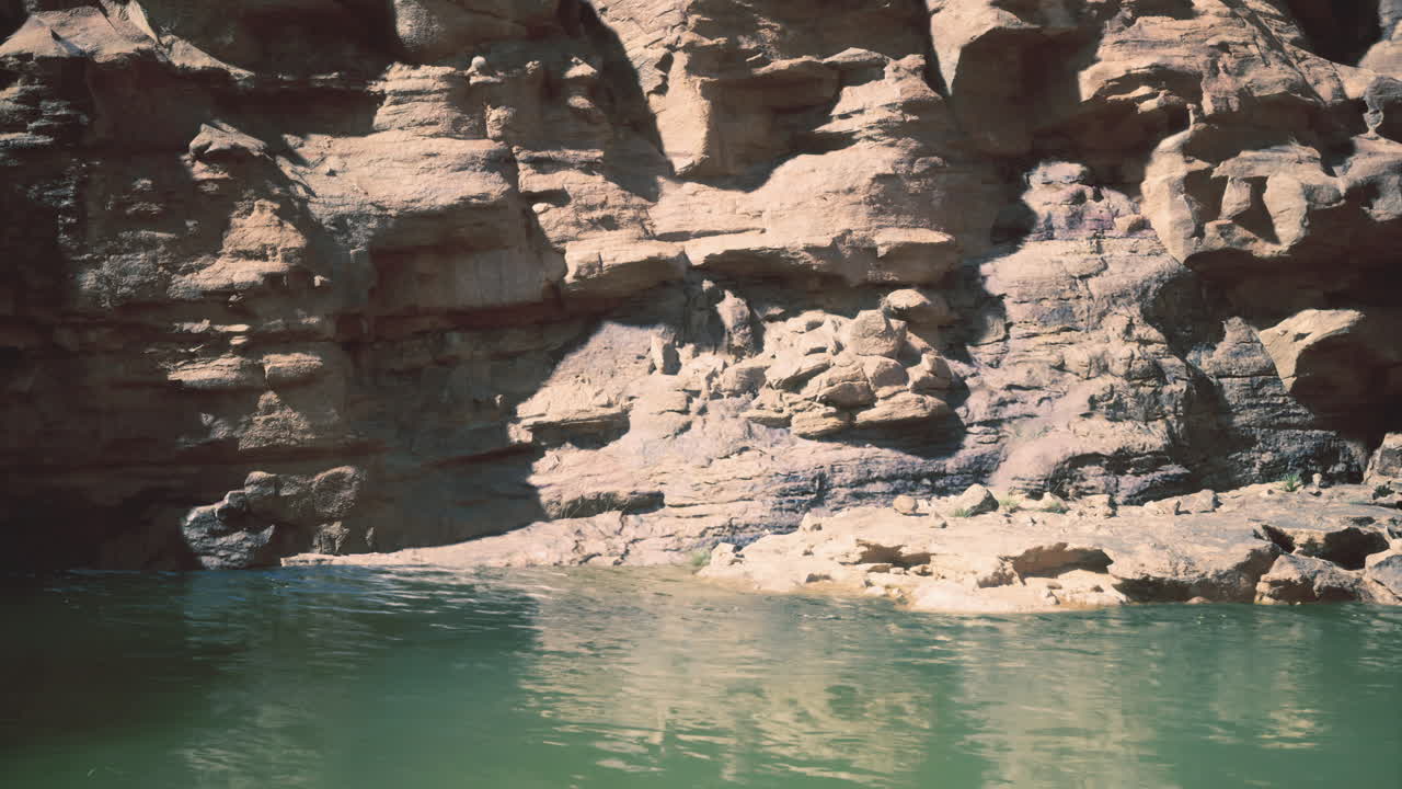 Calm water reflecting rocky cliffs under bright sun at tranquil location