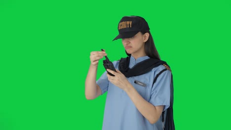 confused indian female security guard trying to fix walkie talkie green screen