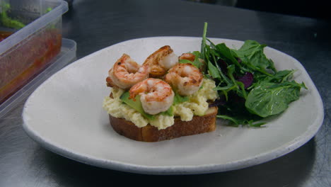 the cook puts lettuce and tomatoes on plate with toast