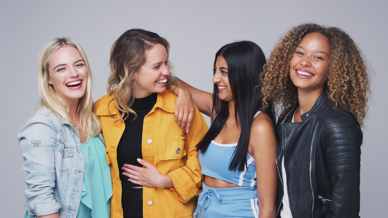 다문화 여성 친구 들 이 슬로우 모션 으로 함께 카메라 에 미소 짓는 그룹 스튜디오 초상화
