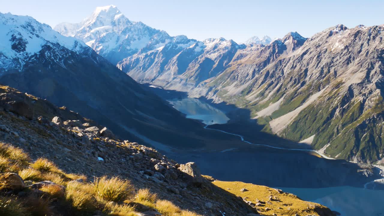 toma panorámica de la cordillera con pico nevado, río que fluye hacia el lago durante el día soleado en el monte cook, nueva zelanda