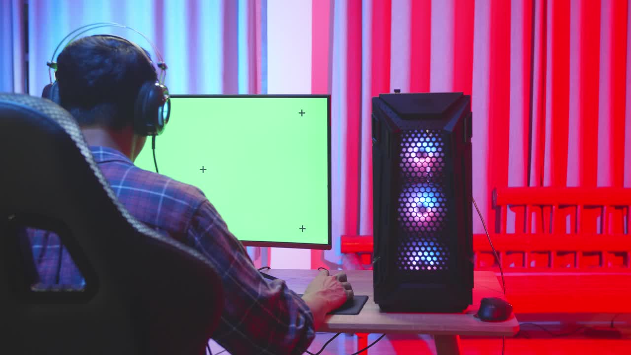 Gamer at home in his setup room with a green screen monitor