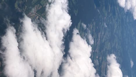 las imágenes de marco vertical capturan la vista hipnótica de las gruesas nubes blancas vistas a través de una ventana de un avión en la radiante luz del día