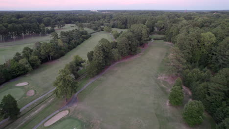 Drone-Aéreo-Durante-La-Puesta-De-Sol,-Campo-De-Golf,-Verde-Exuberante,-Bosques,-Bosque