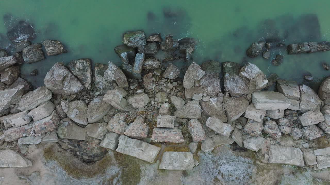 Aerial birdseye view of abandoned seaside fortification buildings at Karosta Northern Forts on the beach of Baltic sea , waves splash, overcast day, wide drone dolly shot moving right