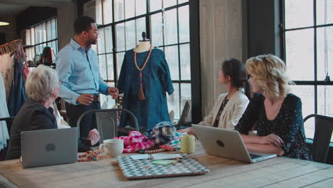 four fashion designers in meeting discussing garment