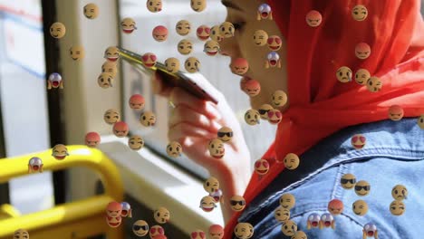 animación de emojis que caen sobre una mujer con hijab usando un teléfono inteligente