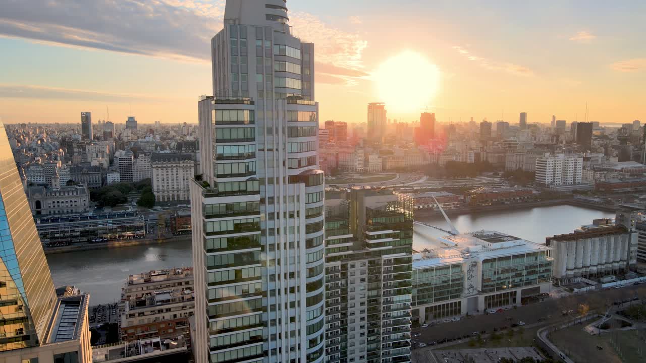 4K Aerial Drone Footage of Puerto Madero Reverse Dolly Shot Up Close to Apartment Building with Beautiful Sunset Over City Skyline.