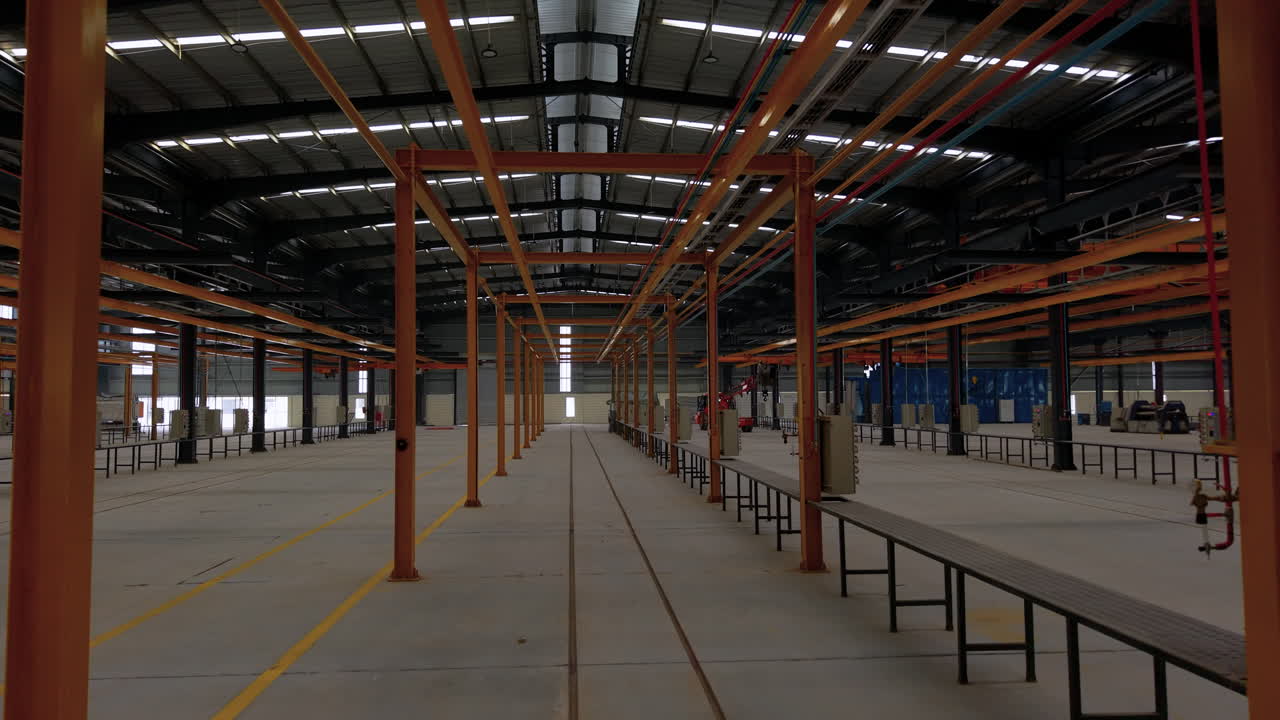 Wide interior shot of a spacious empty industrial warehouse with overhead cranes and production lines. Ideal for engineering, logistics, and manufacturing concepts