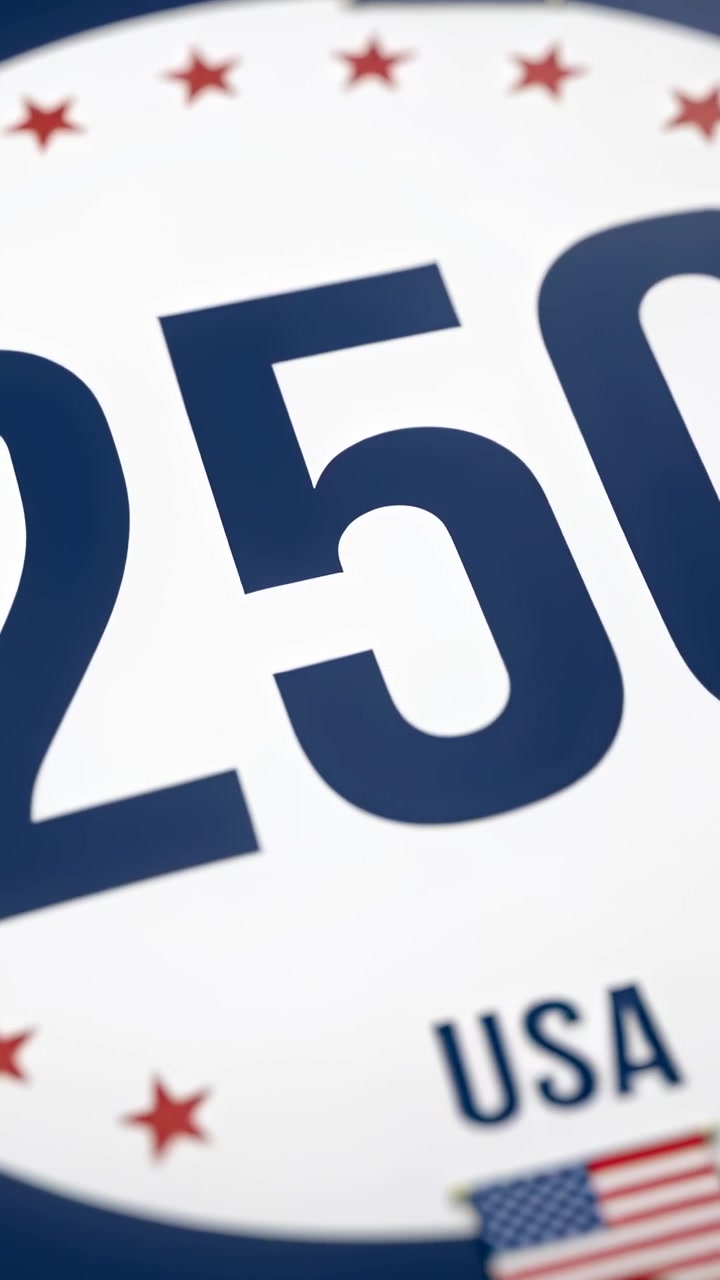 Video verticale: Panoramica della telecamera che rivela un emblema circolare rotante con il numero 250 al centro, in uno studio, con la bandiera USA.