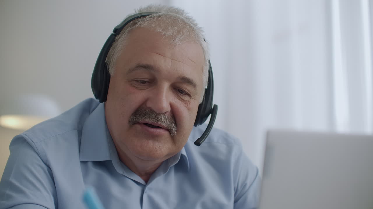 uomo ciccione di mezza età con baffi sta usando le cuffie con microfono per comunicare con i colleghi in chat online