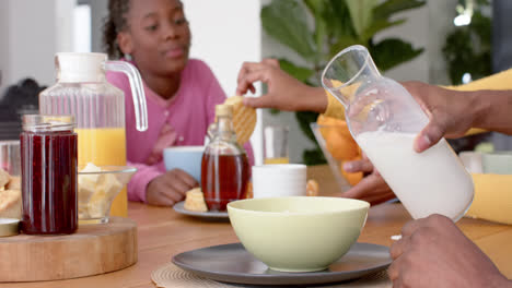 padres afroamericanos con hijo e hija comiendo el desayuno en la mesa en la cocina, en cámara lenta