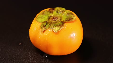 a persimmon rotates on a dark background