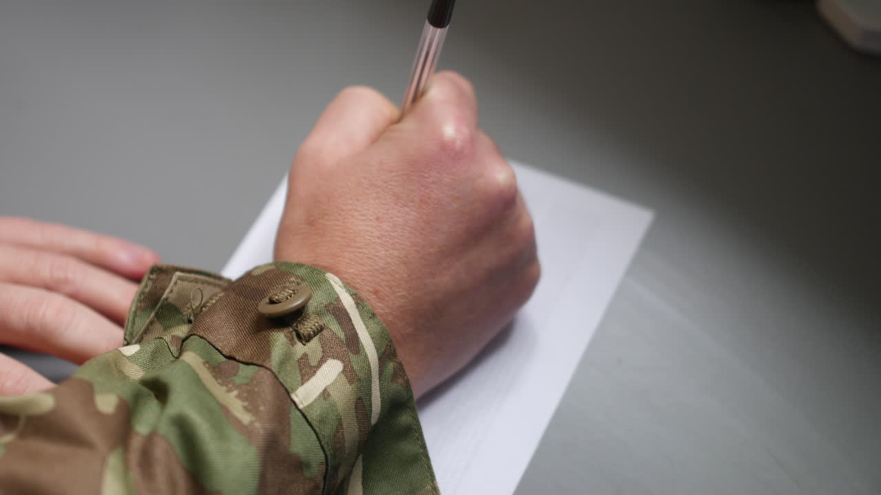 un soldado marino del ejército escribiendo una carta en una pieza de papel con un bolígrafo