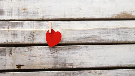 Red-heart-paper-cut-pinned-on-the-rope-against-wooden-surface-4k