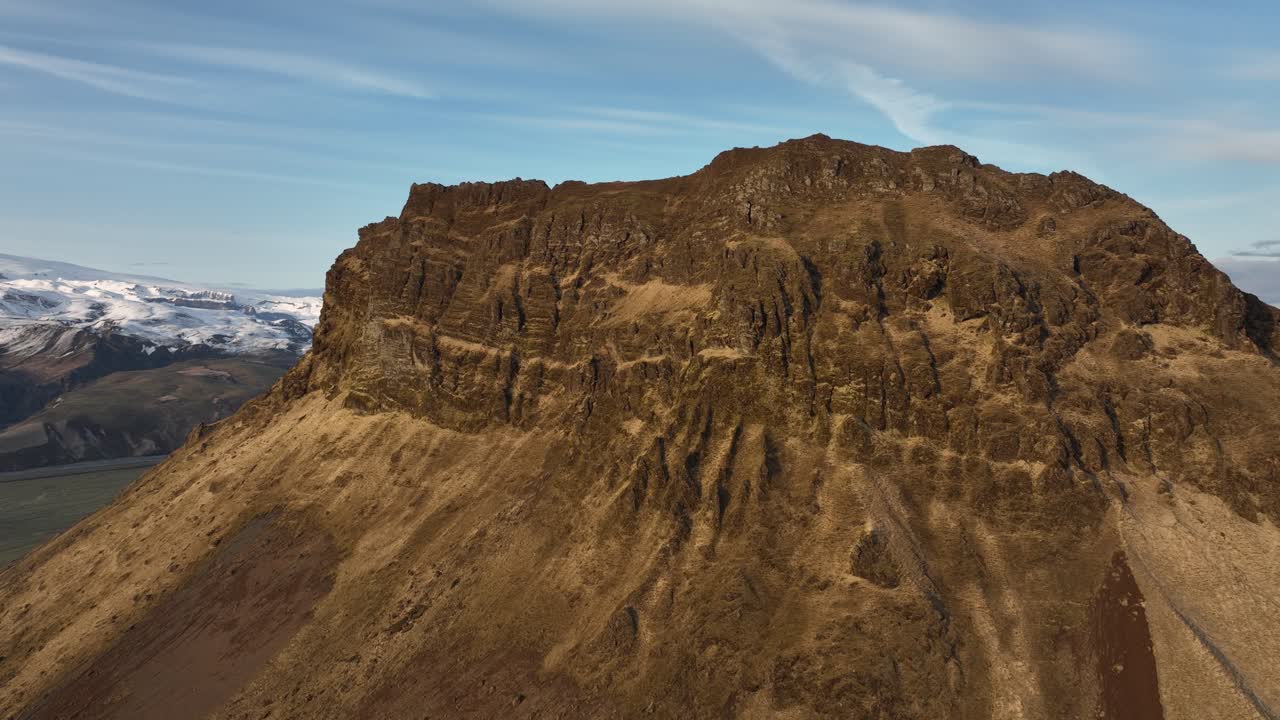 아이슬란드 부르펠 (búrfell) 에 있는 높은 바위 절벽의 드론 촬영, 극적인 질감과 멀리 있는 눈으로 인 산들이 인상적인 풍경을 만니다.