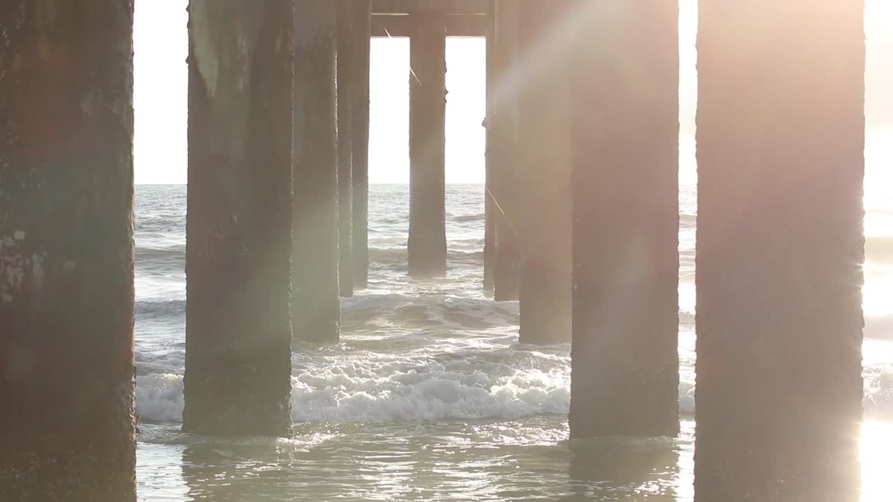 해변 부두 아래에서 햇빛으로 천천히 기울이기
