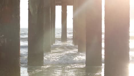 slow tilt into the sunlight under a beach pier