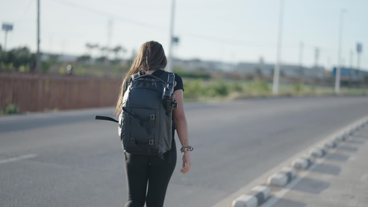 Mujer con mochila caminando por una carretera