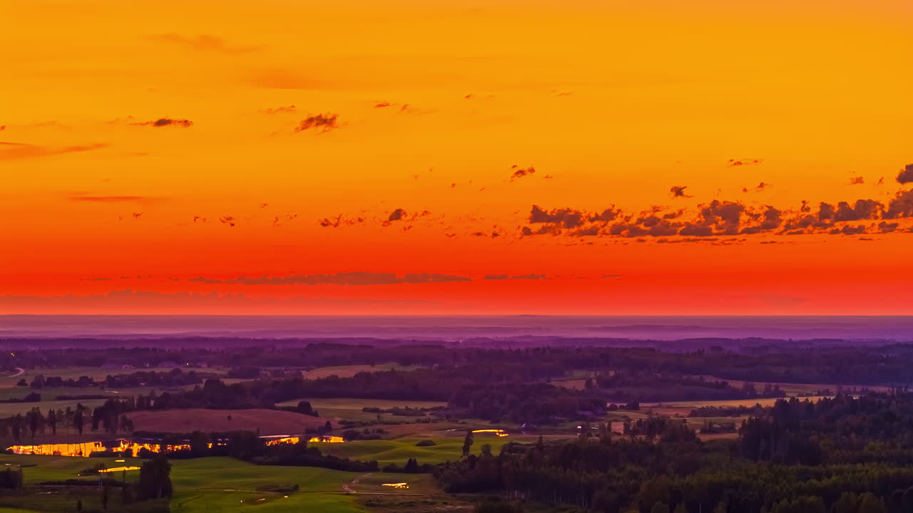 Glowing orange sunset over farmland with scattered clouds, space for text in sky