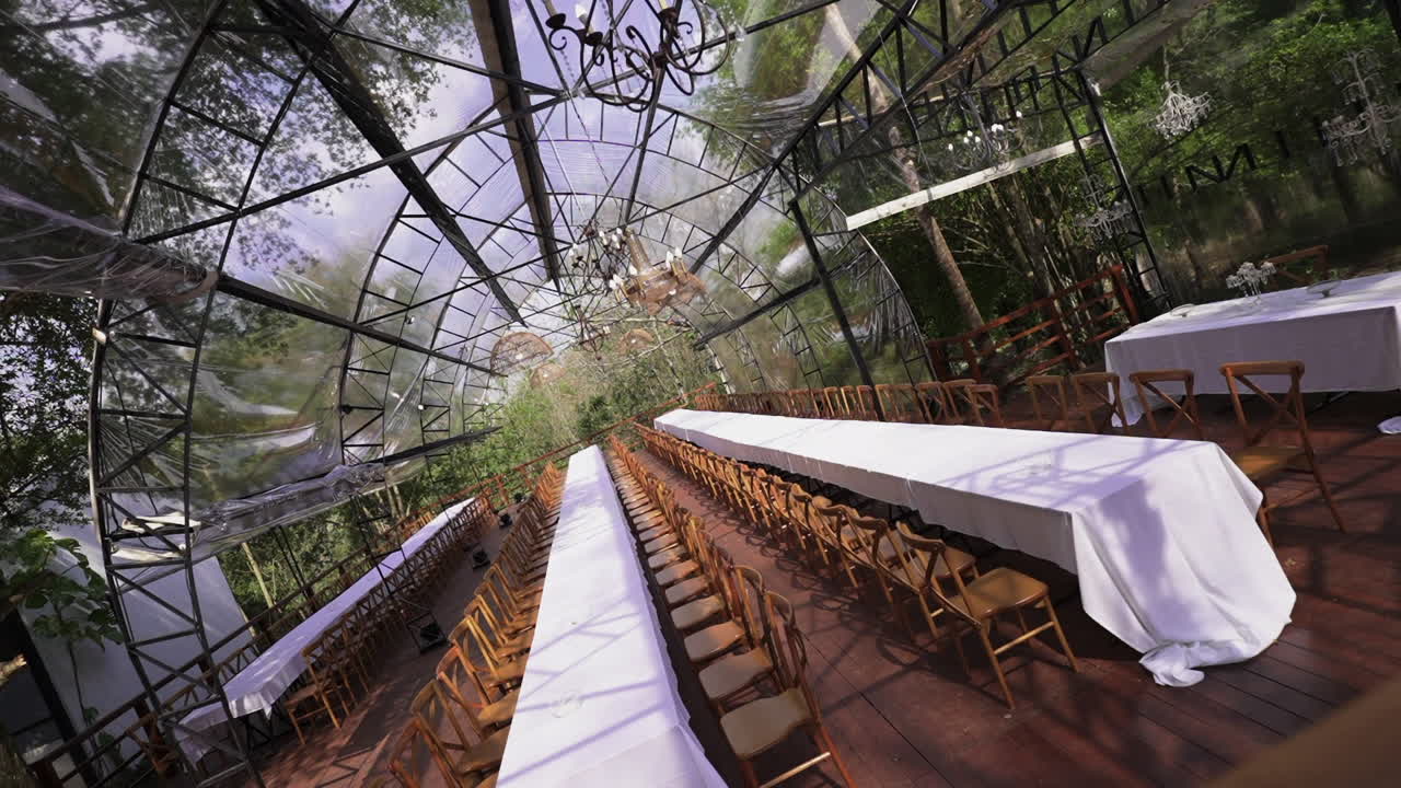 Glass gazebo in tropical forest prepared with long tables for elegant wedding reception, premium event, Parana, Iguazu, Argentina