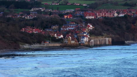 low establishing drone shot of robin hood's bay at low tide uk