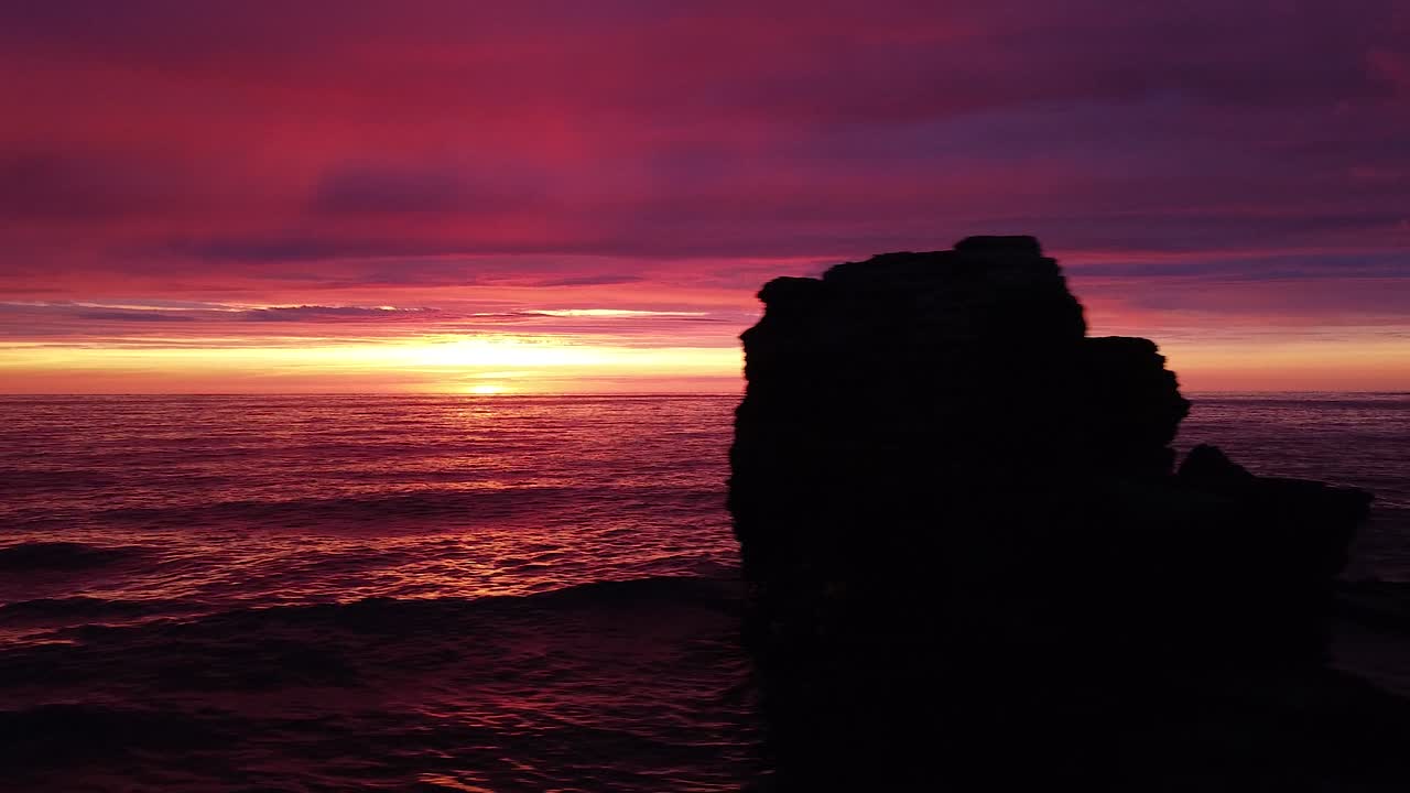 hermosa antena vibrante alto contraste rosa púrpura puesta de sol sobre el mar báltico, puerto de guerra de karosta ruinas de fortificación de la costa de hormigón en liepaja, gran angular drone dolly shot moviéndose a la izquierda