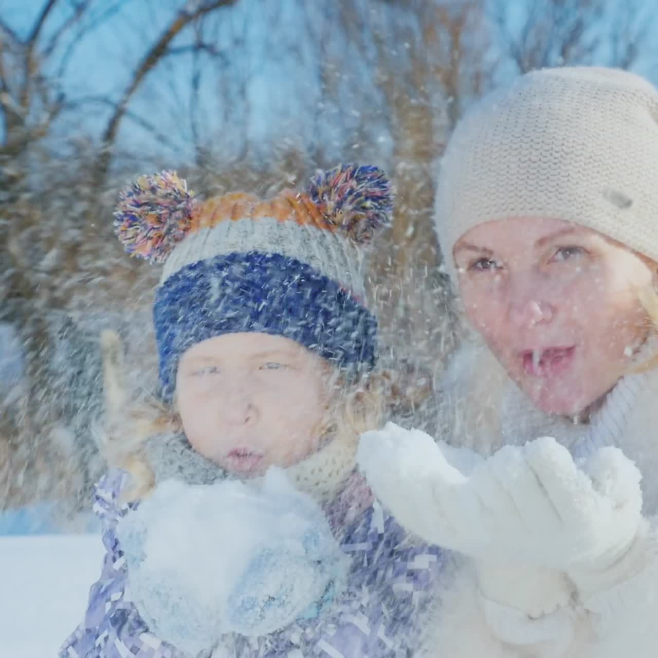 아이를 안고 있는 여자는 겨울과 눈 속에서 기뻐한다