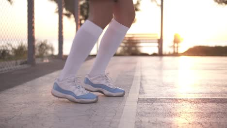 primer plano de las piernas de una jugadora de baloncesto haciendo ejercicio de goteo muy rápidamente sin balón, entrenando al aire libre en la cancha local