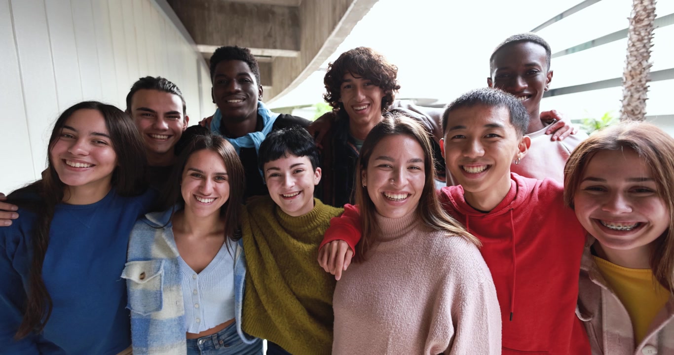 Gruppo eterogeneo di giovani amici felici che sorridono alla fotocamera