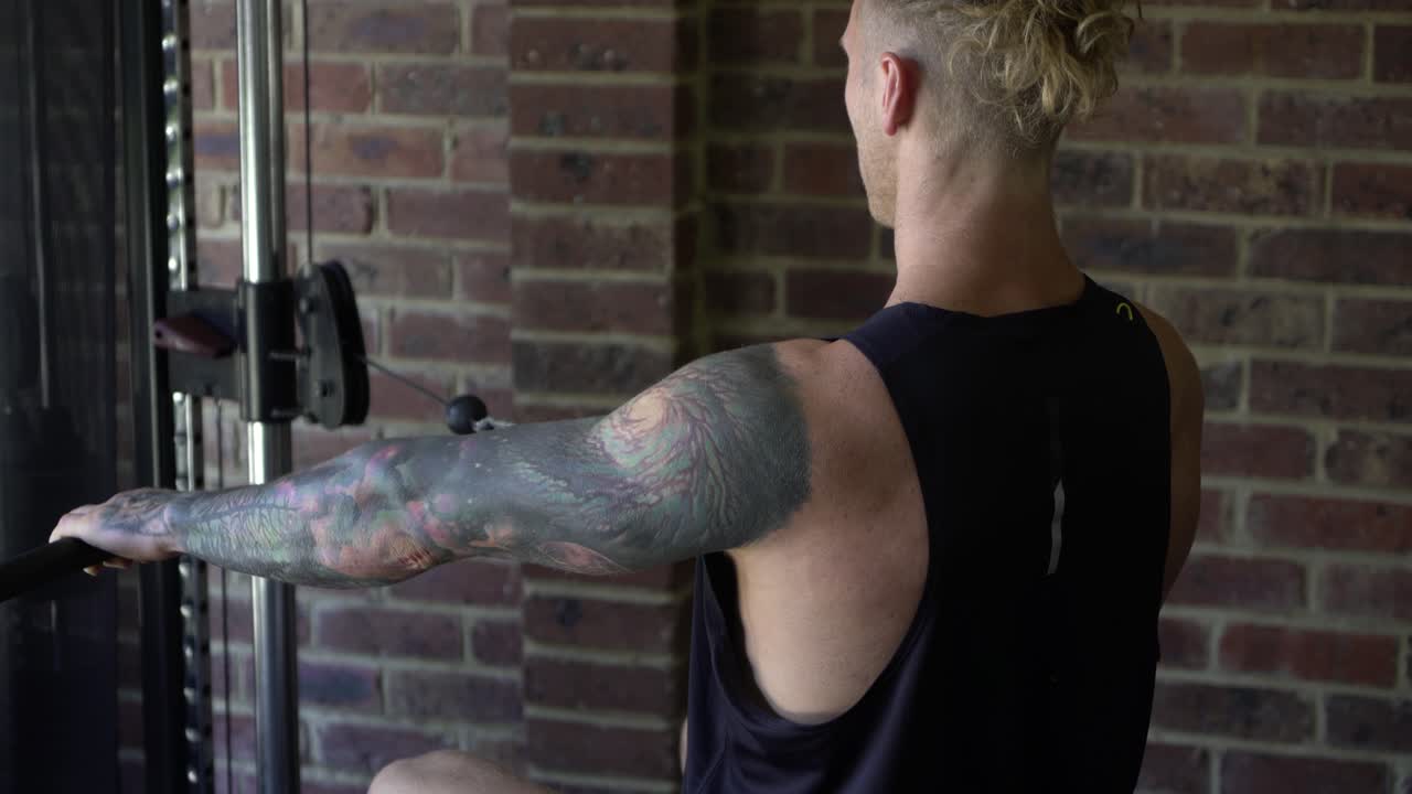 Tattoo man muscles in home gym doing lat rows