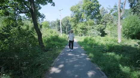 young man walking with guitar on street near forest