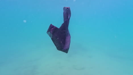 plastic bag floats underwater in clear tropical sea creating pollution hazard