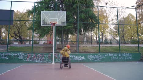 disabled young man plays basketball with his girlfriend on an outdoor basketball court.