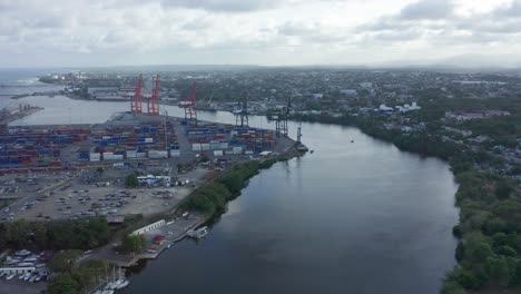 haina port full of shipping containers and large cranes sitting on the river on an overcast day