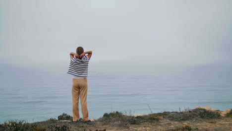 Relaxed-woman-enjoying-ocean-landscape-vertical.-Carefree-girl-stretching-cliff