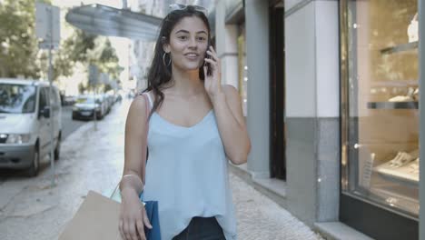 happy young woman standing on street and talking on phone