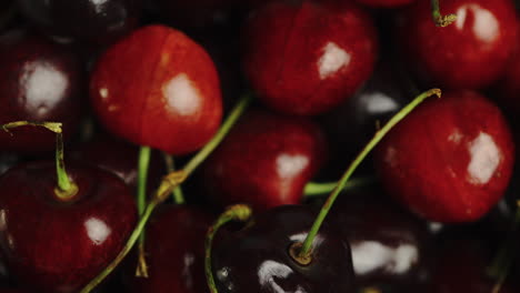 close up of bright red cherries in a bowl, firstly being picked up and then being dropped back in