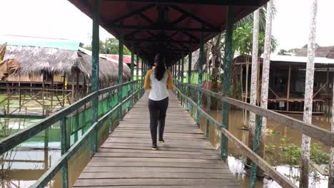 peruvian girl walking through a bridge in a jungle town