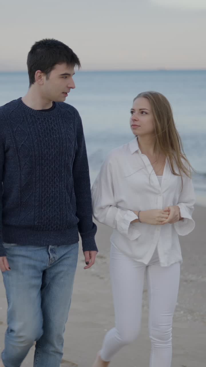 Couple Walking and Talking on a Beach at Dusk