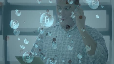 múltiples símbolos de bitcoin flotando contra el hombre con tableta digital hablando en el teléfono inteligente