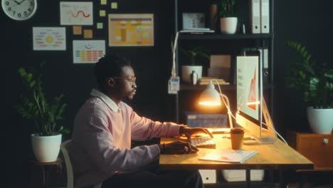young businessman walking in office and using computer at desk