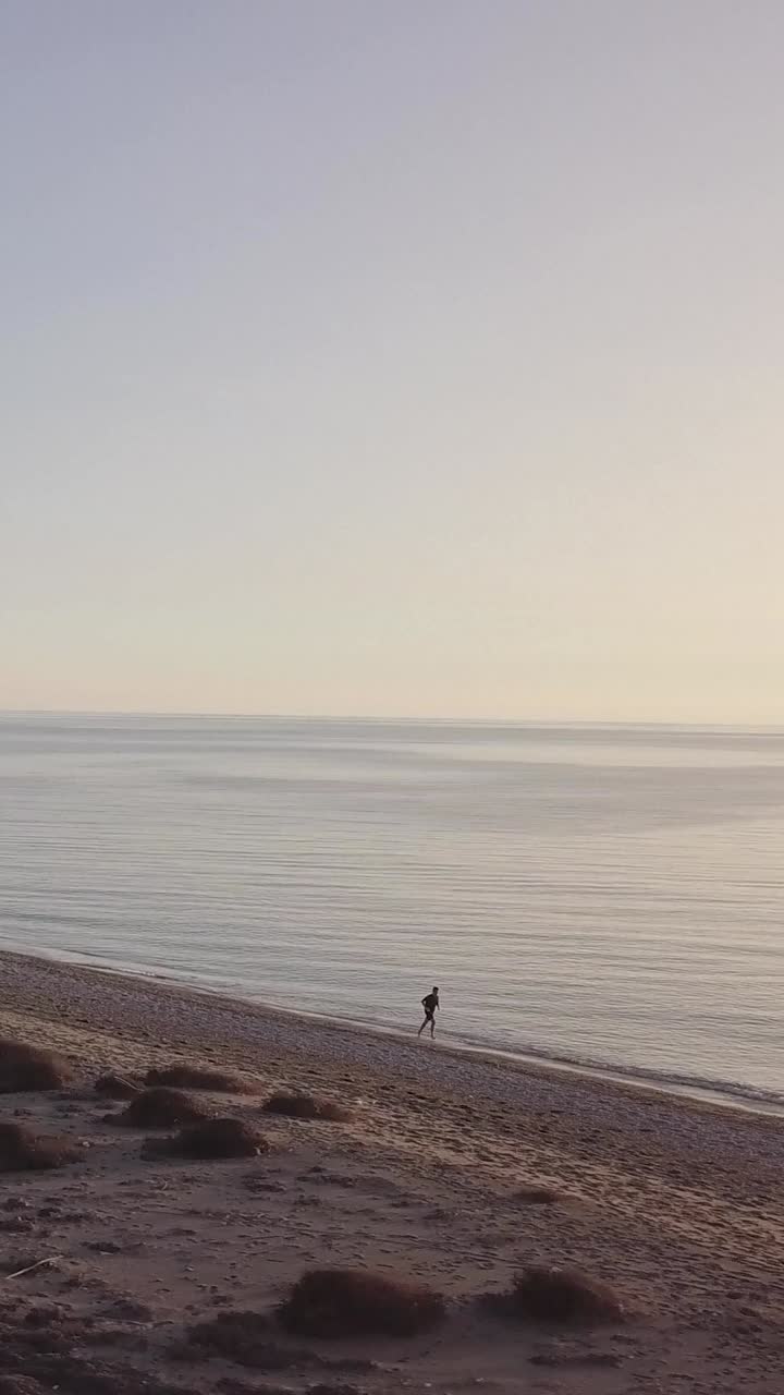 Man running on the beach. Orbital shot with drone