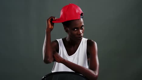 androgynous man posing with red cap