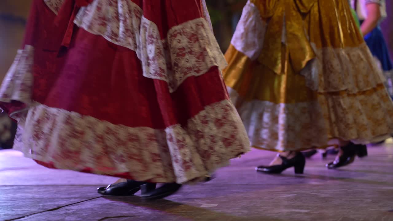 primer plano de una línea de mujeres bailarinas folclóricas mexicanas con zapatos y vestidos en movimiento.