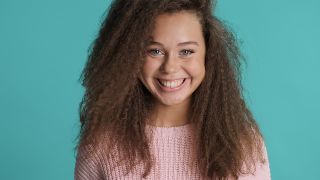 una mujer caucásica de cabello rizado asintiendo delante de la cámara.